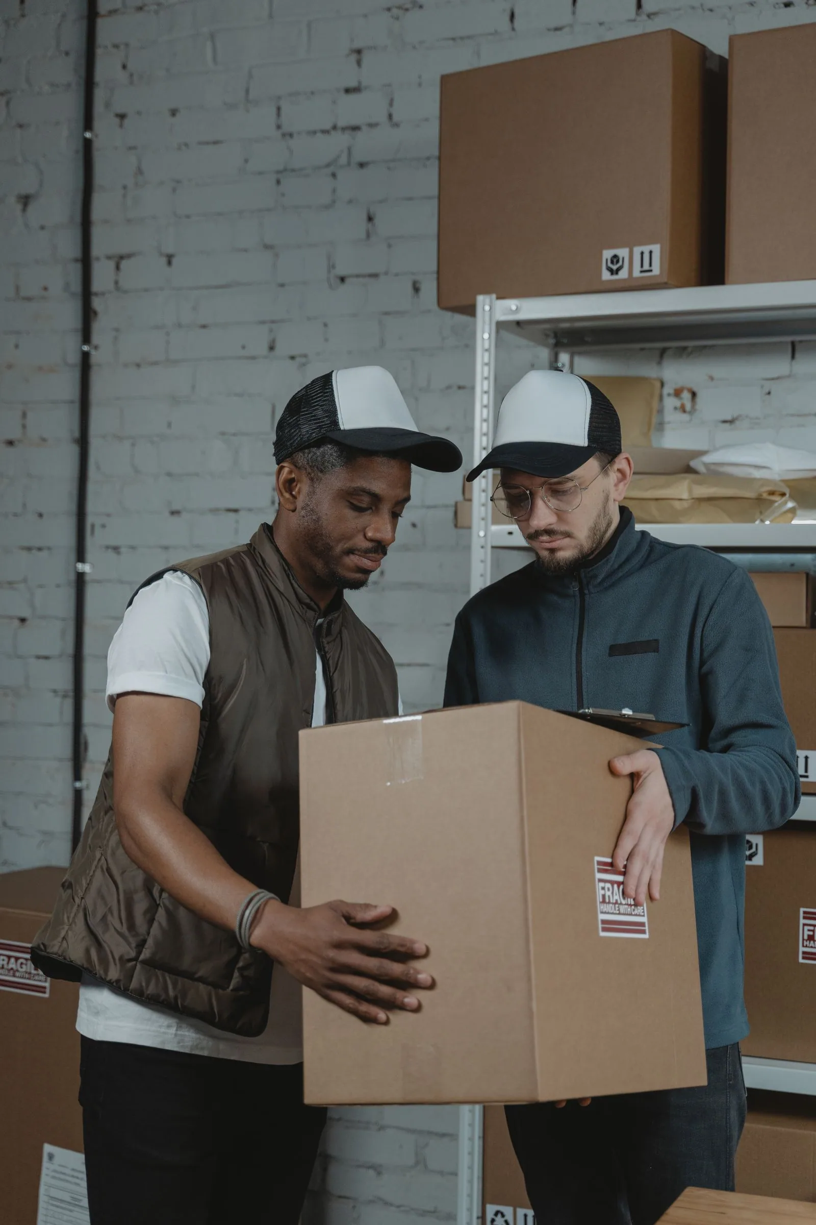 Two warehouse colleagues checking a document on a parcel