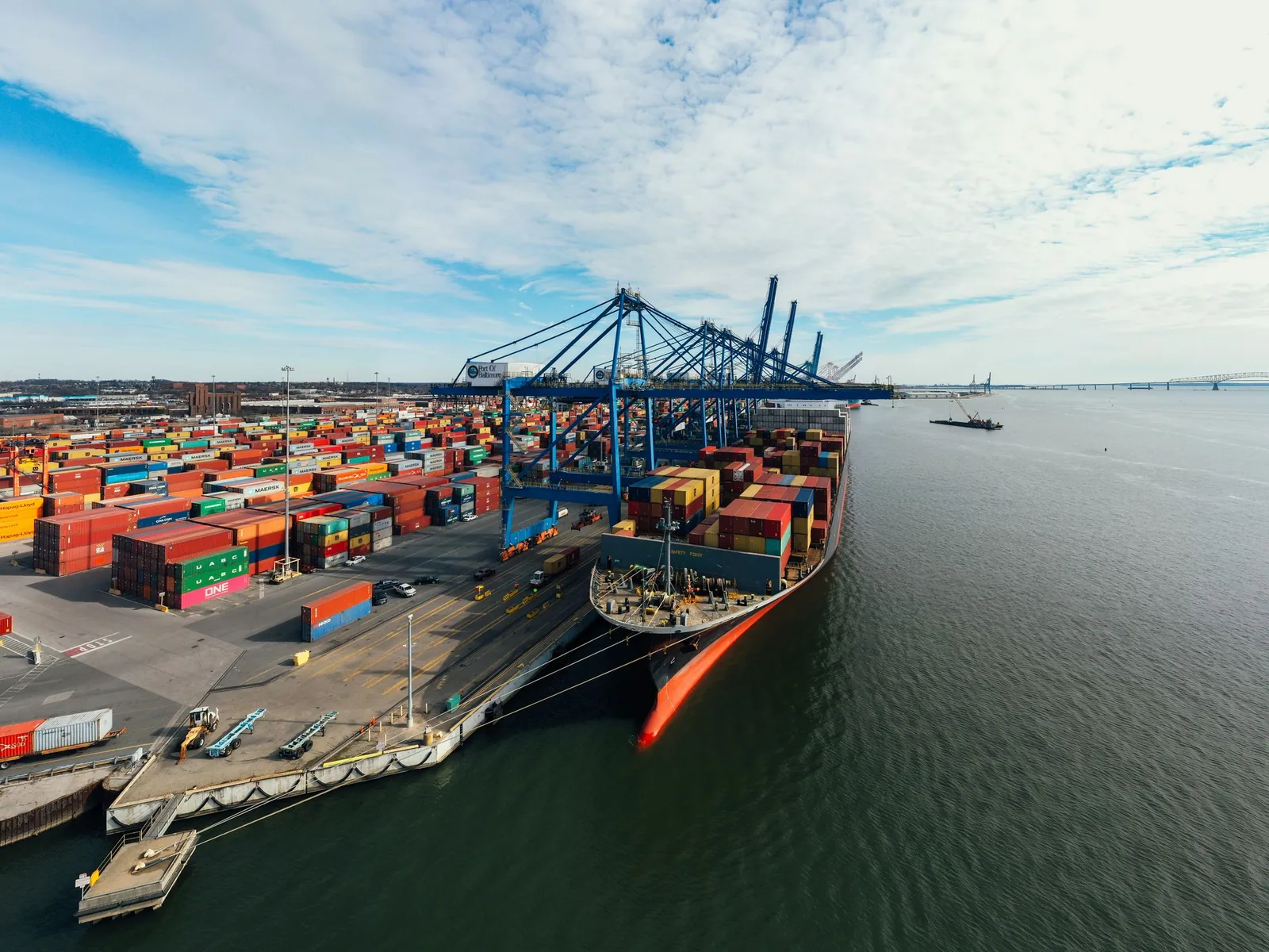 A container ship alongside working cranes at the port of Baltimore
