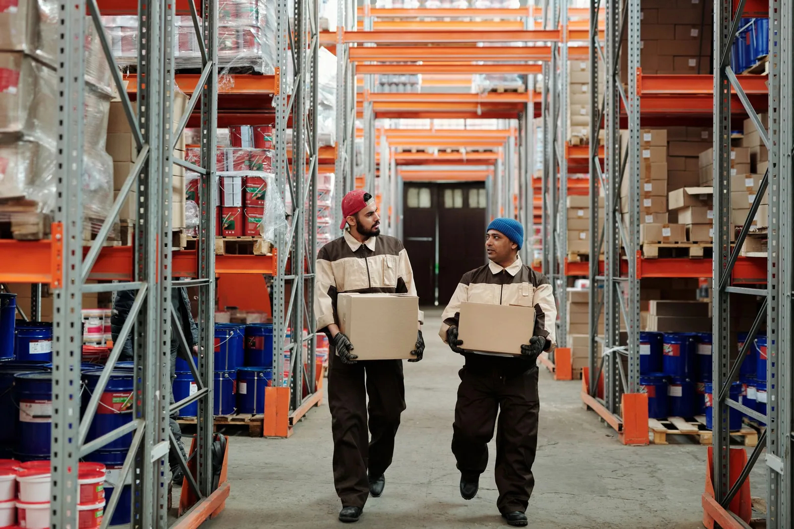 Warehouse workers moving cartons between storage racks