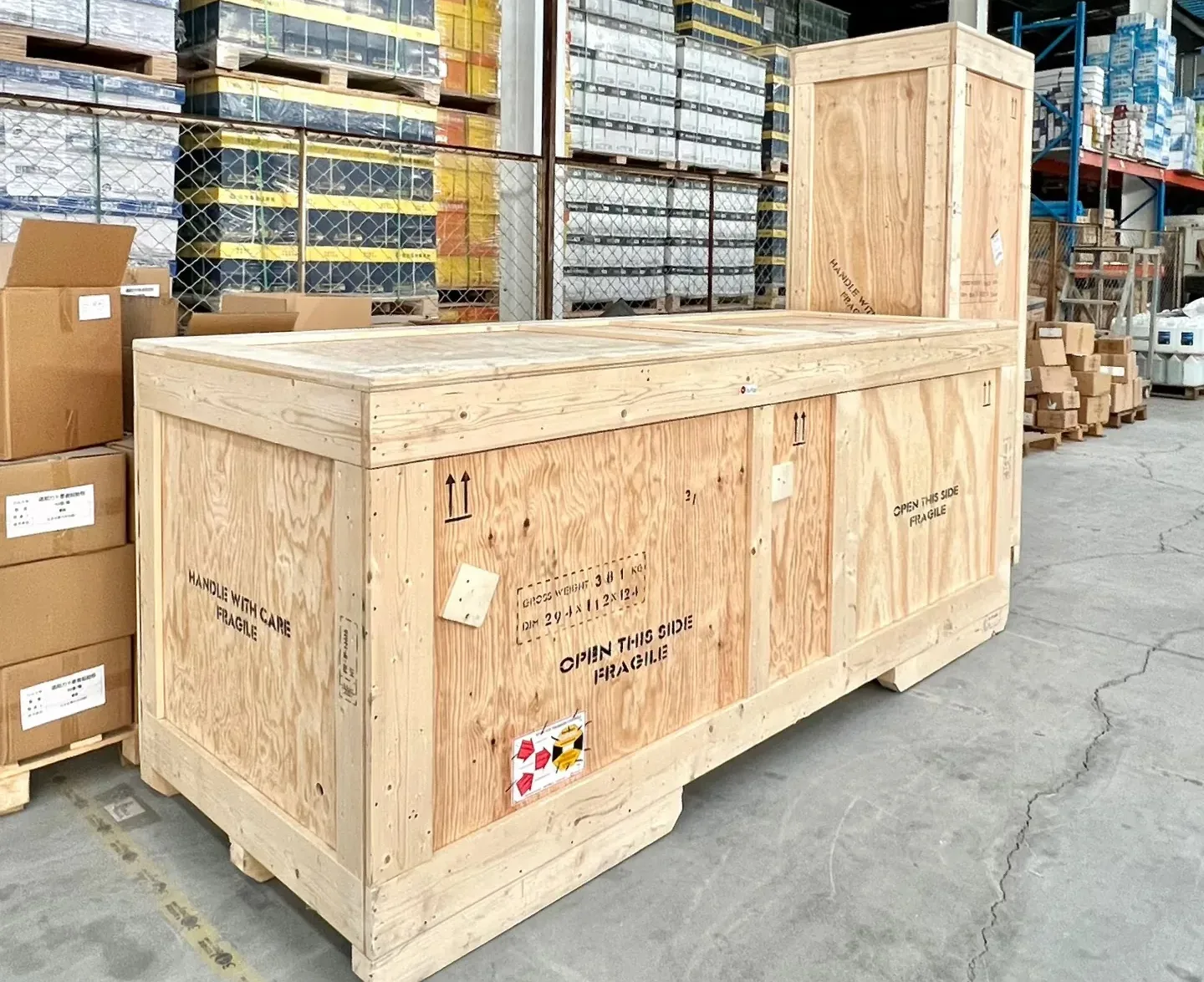 A plywood export crate and cartons staged in a warehouse aisle