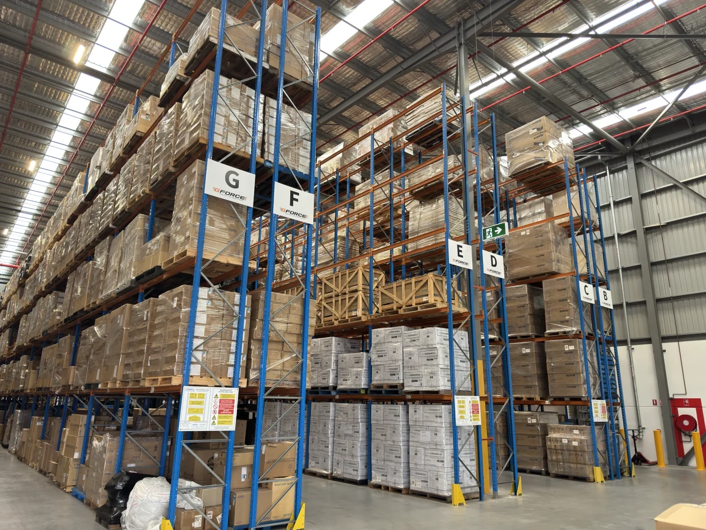 Pallet racks, marked aisles and stored cargo in a working warehouse.