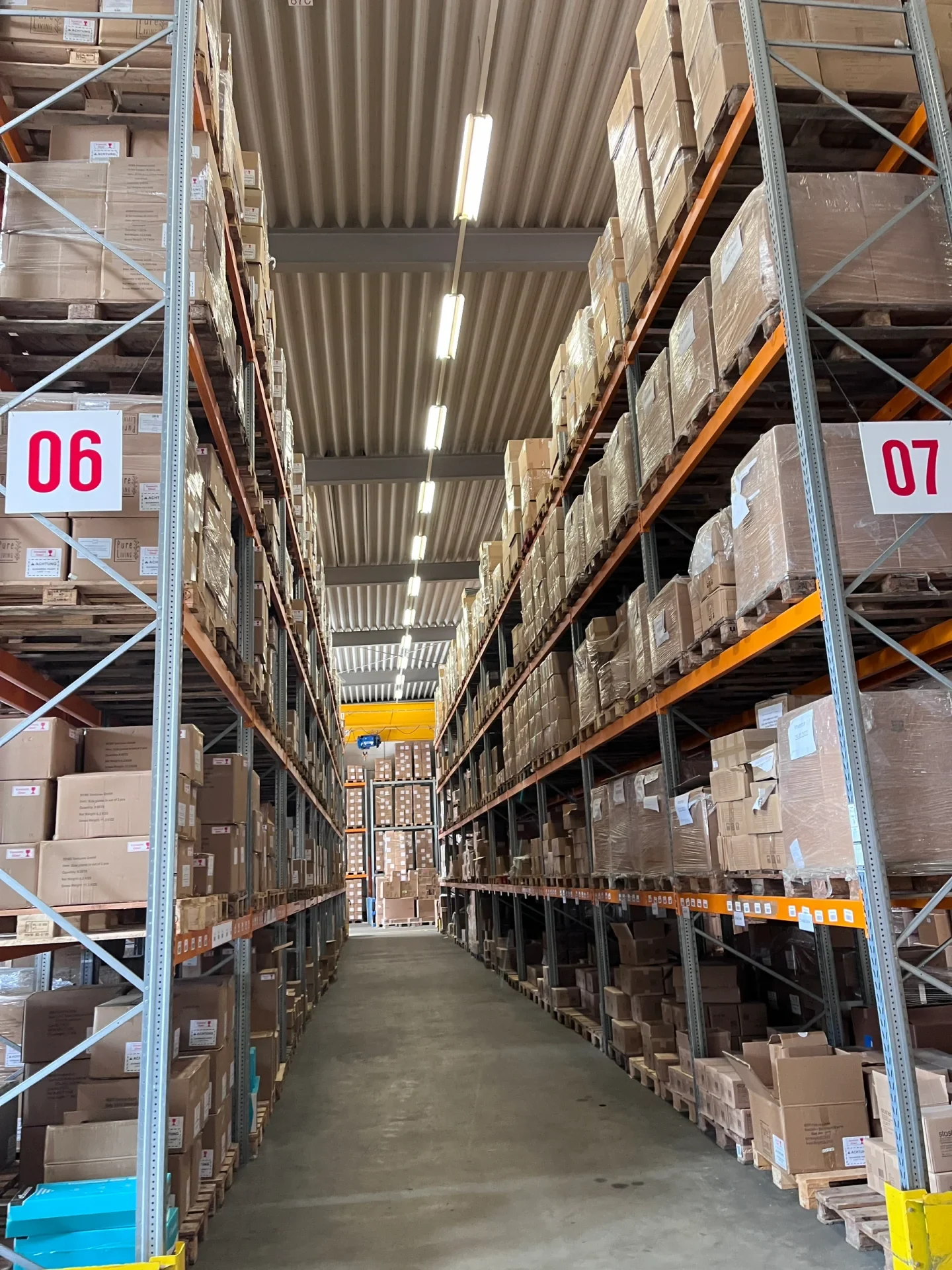 Pallet racks, marked aisles and stored cargo in a working warehouse.