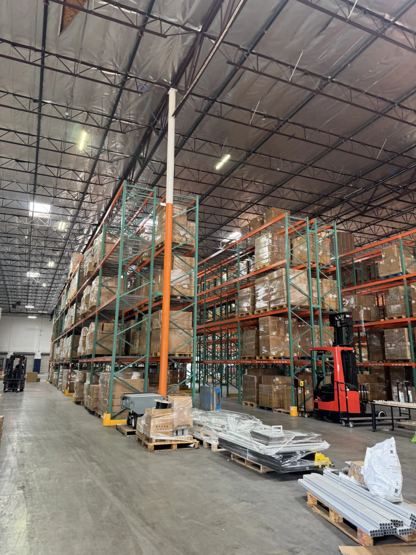 Pallet racks, marked aisles and stored cargo in a working warehouse.