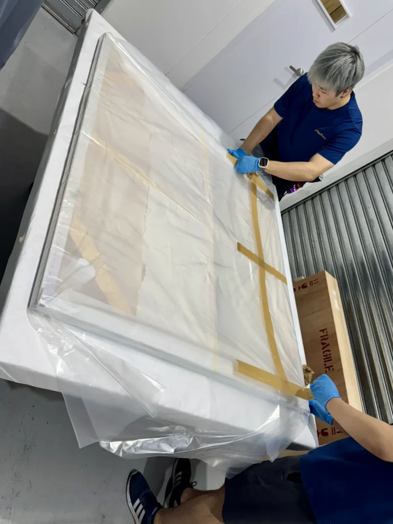 A worker assembling protective layers and inner packaging around goods.